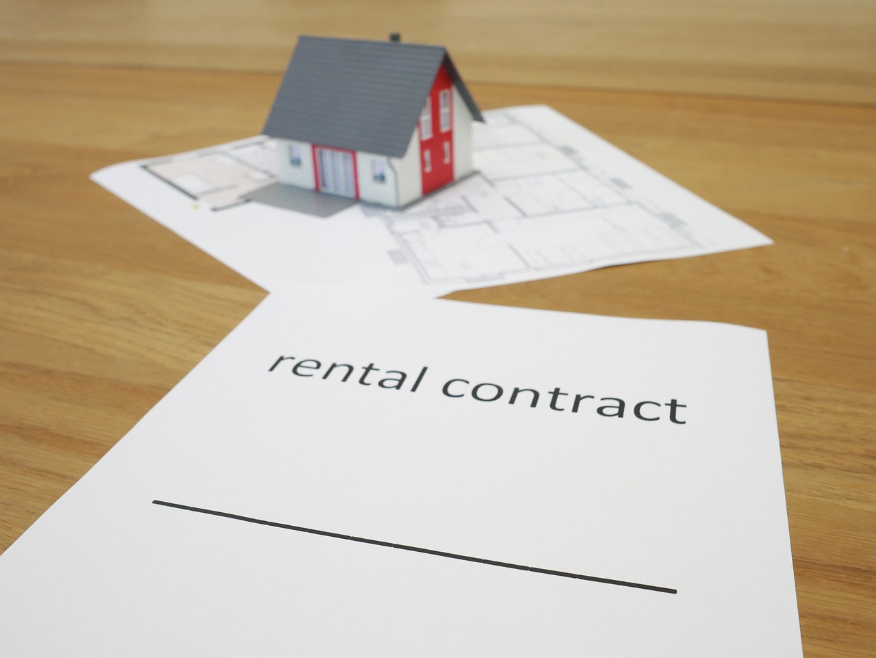 casetta in miniatura su foglio di contratto di affitto 4+4
