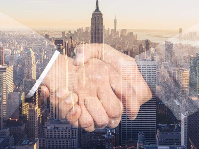 stretta di mano su sfondo di grattacieli per contratto ad uso foresteria