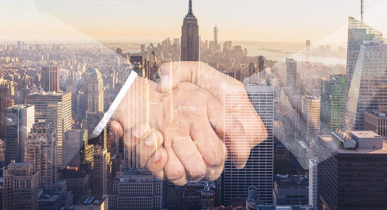 stretta di mano su sfondo di grattacieli per contratto ad uso foresteria