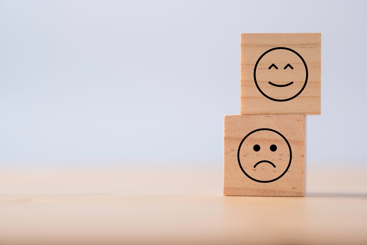 Due emozioni di felicità e tristezza che vengono stampate su un cubo di legno per indicare pro e contro di valutazione casa online
